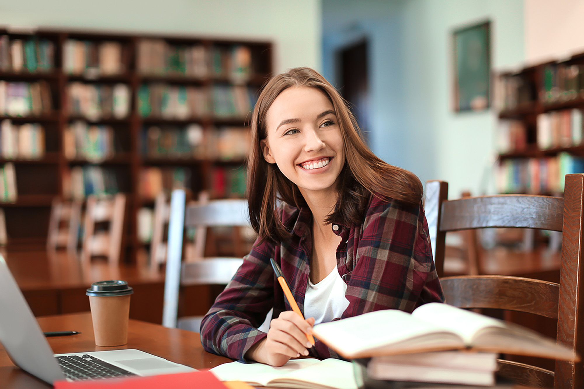 a woman looking over at books at a desk in a library