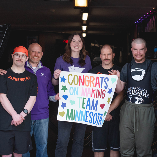 a group of people holding a banner that says "Congrats on Making Team Minnesota"