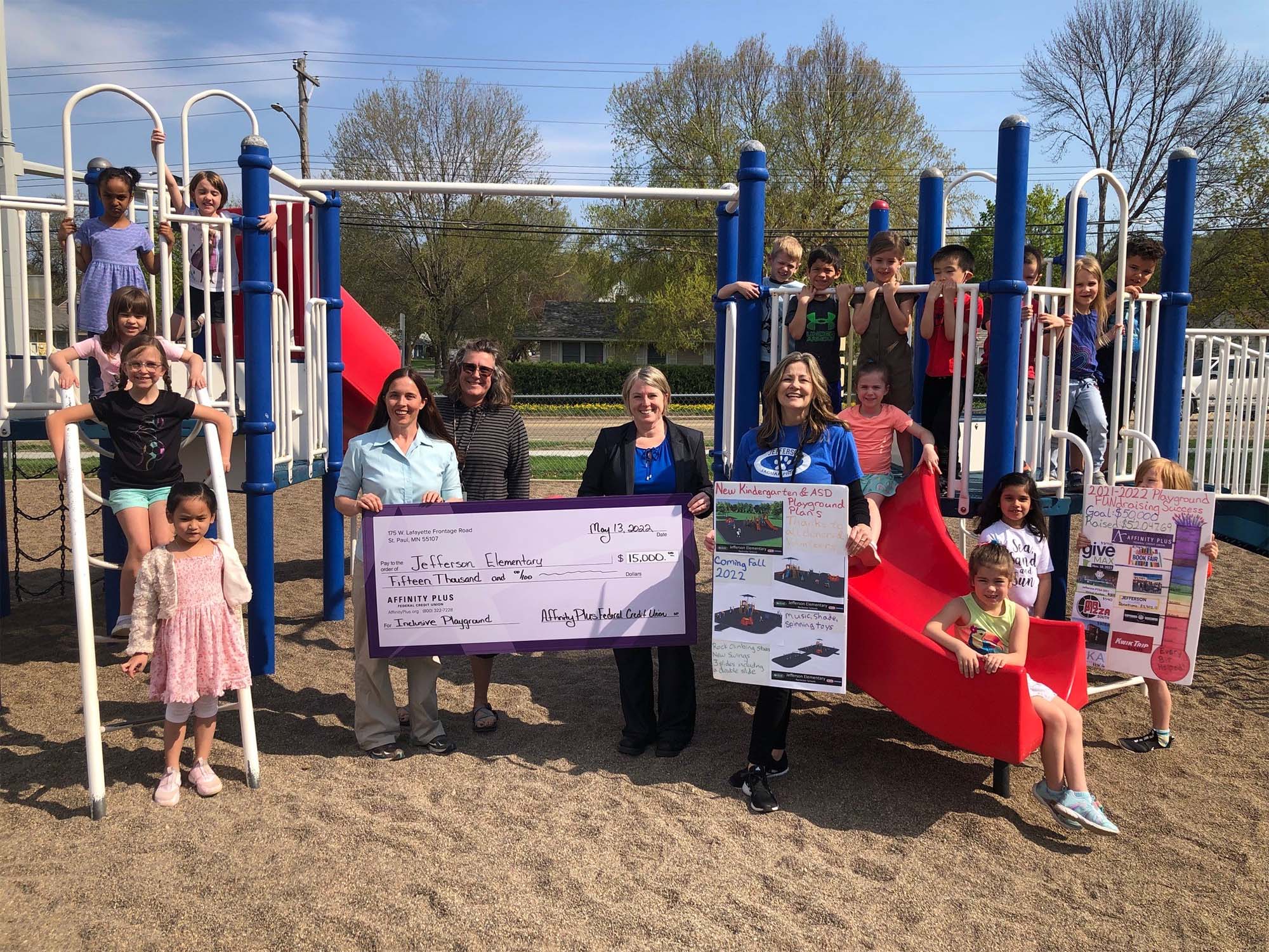 A group at a playground holding a check