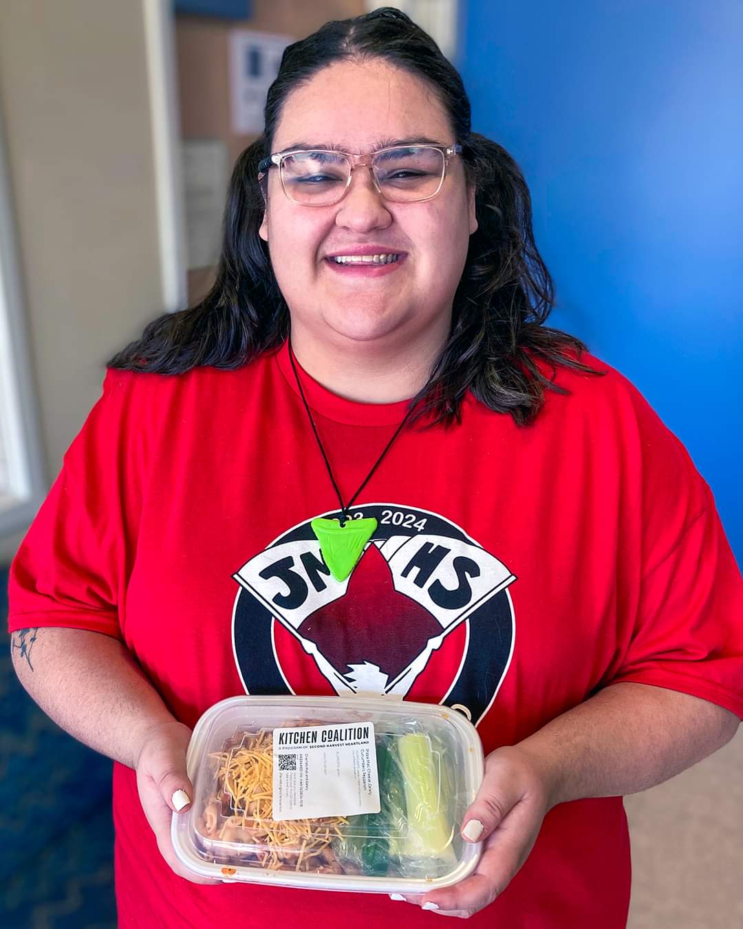 A person holding a prepared meal from Kitchen Coalition