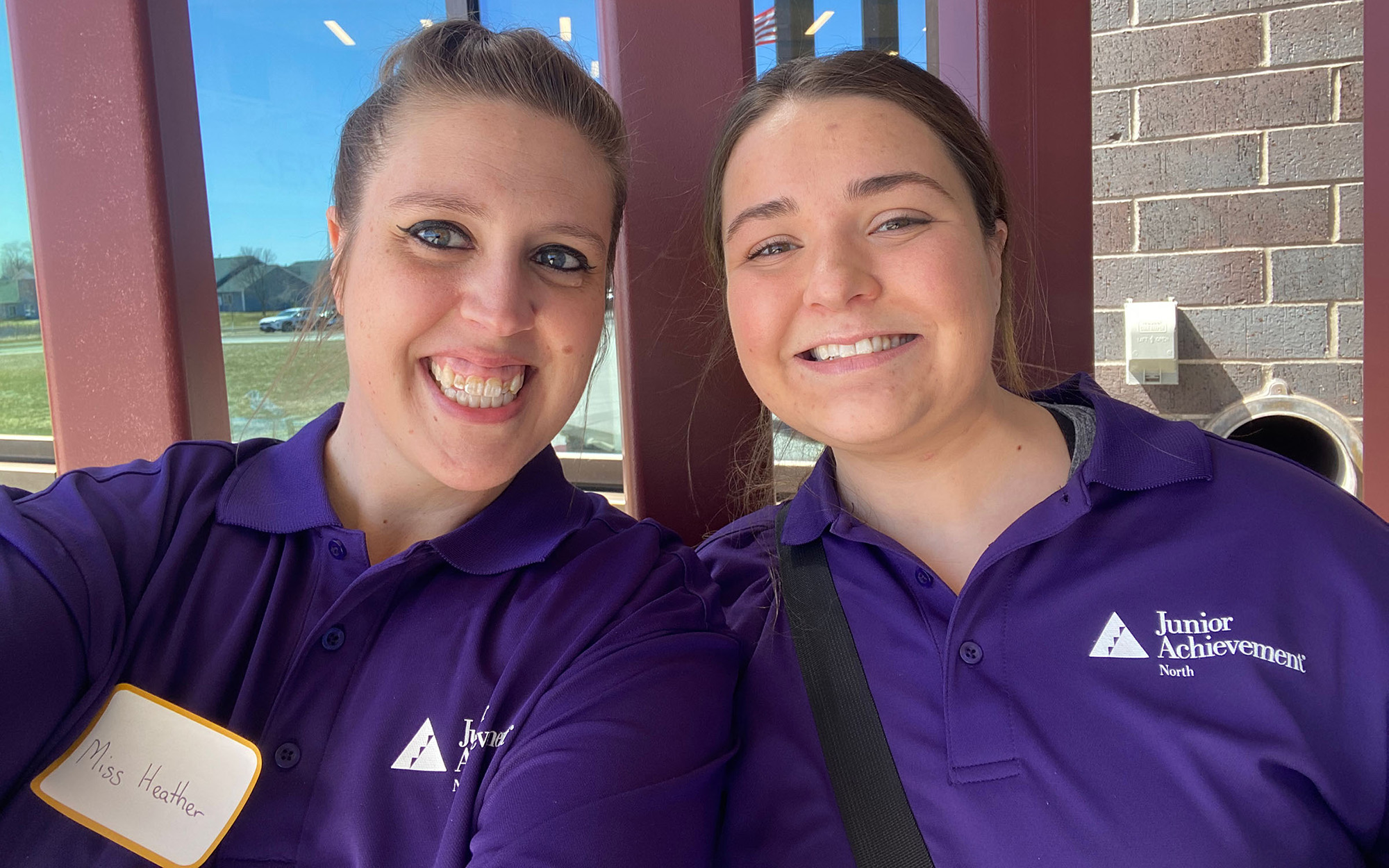 Two employees smiling wearing purple Junior Achievement shirts
