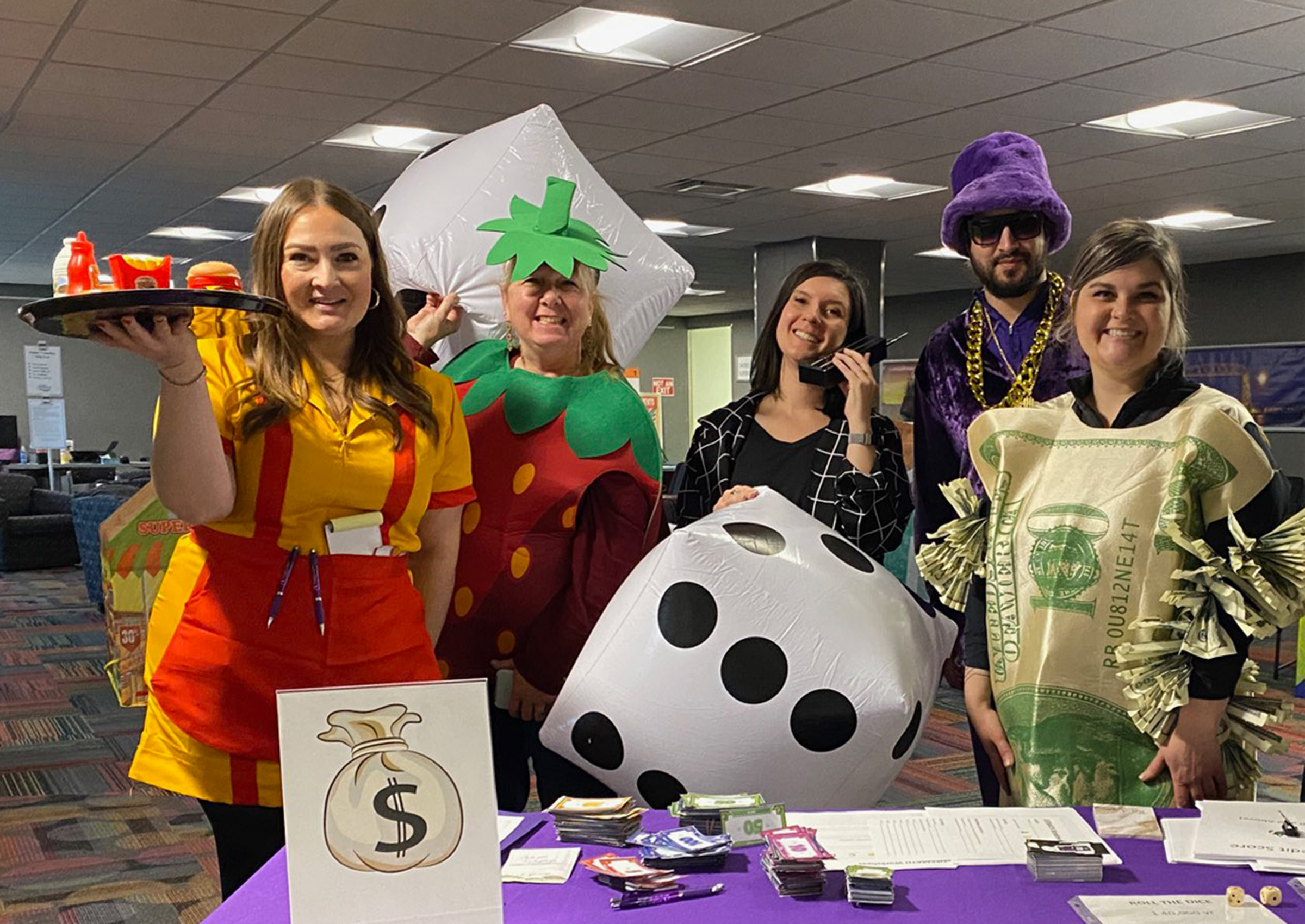 5 people in various costumes with a game on table in front of them