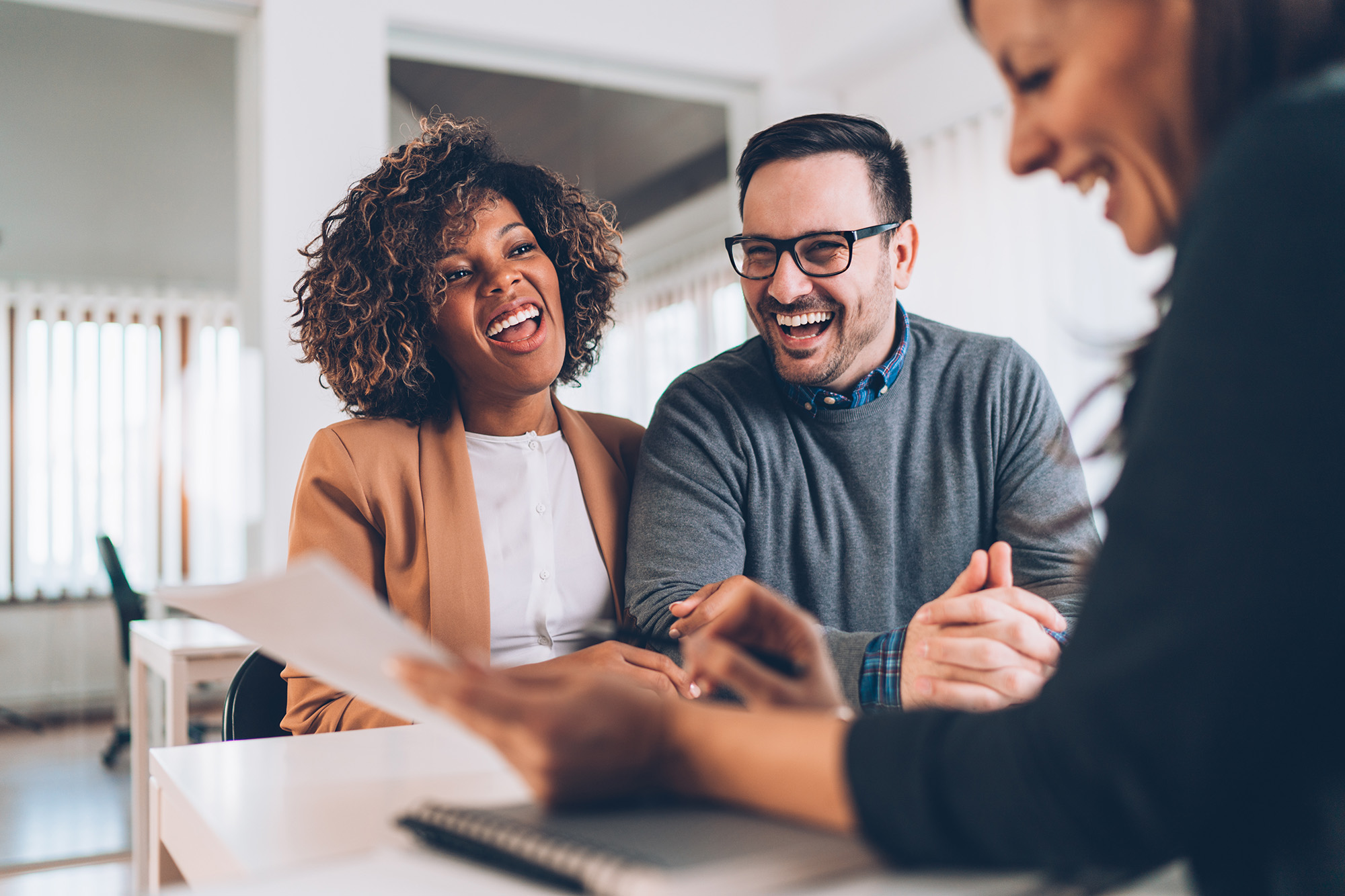 A couple interacting with a woman looking over paperwork
