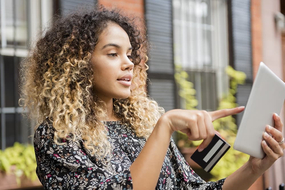 Young woman with credit card looking at ipad