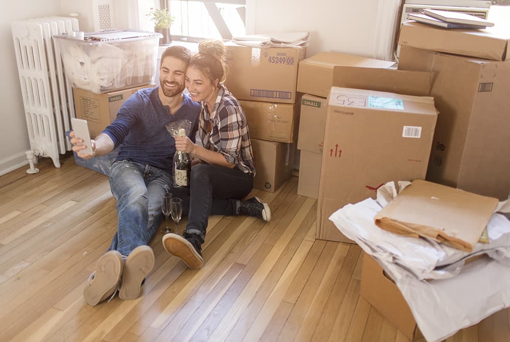 Young couple taking selfie sitting against moving boxes