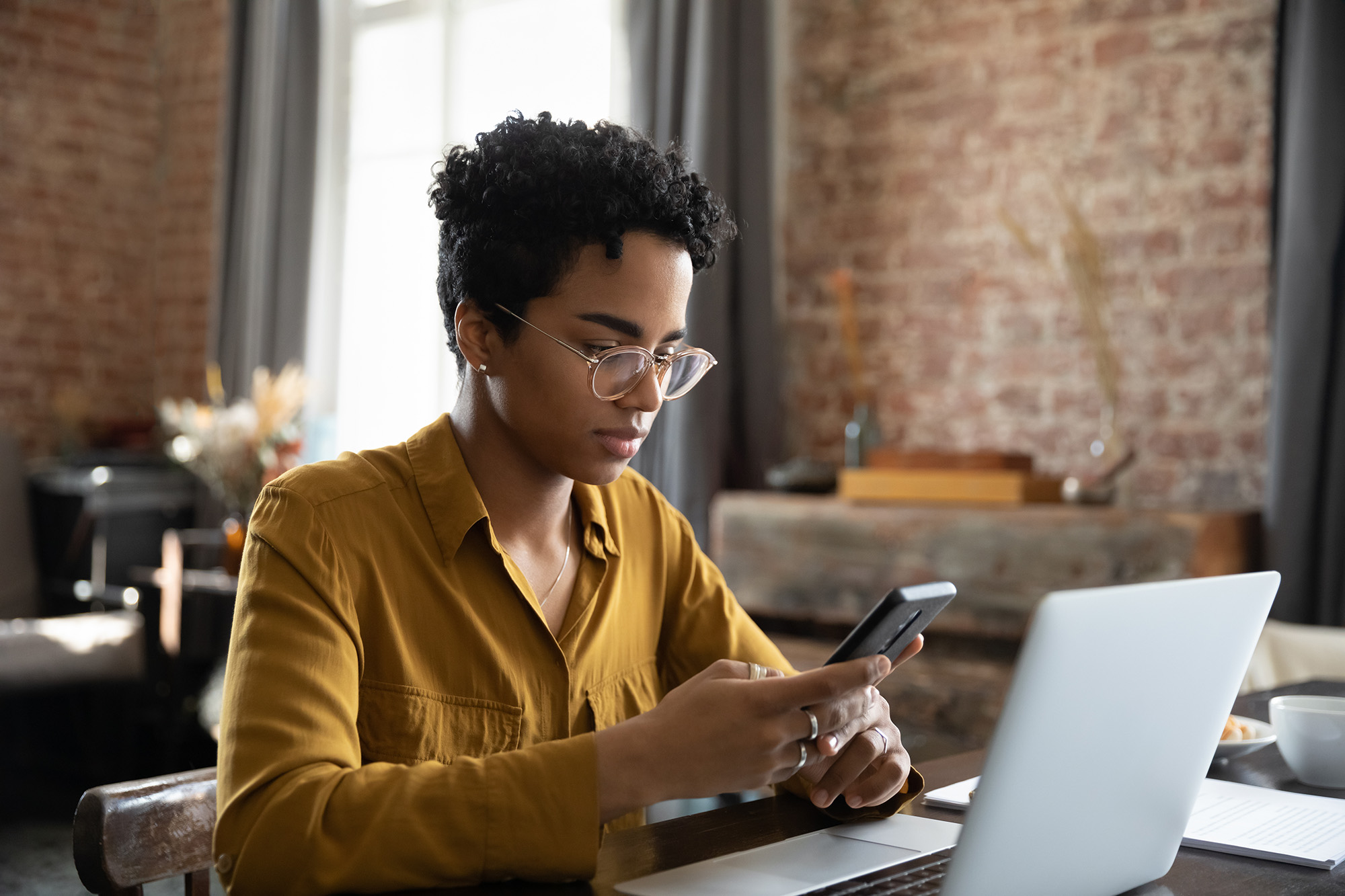 a woman on a phone in front of a laptop