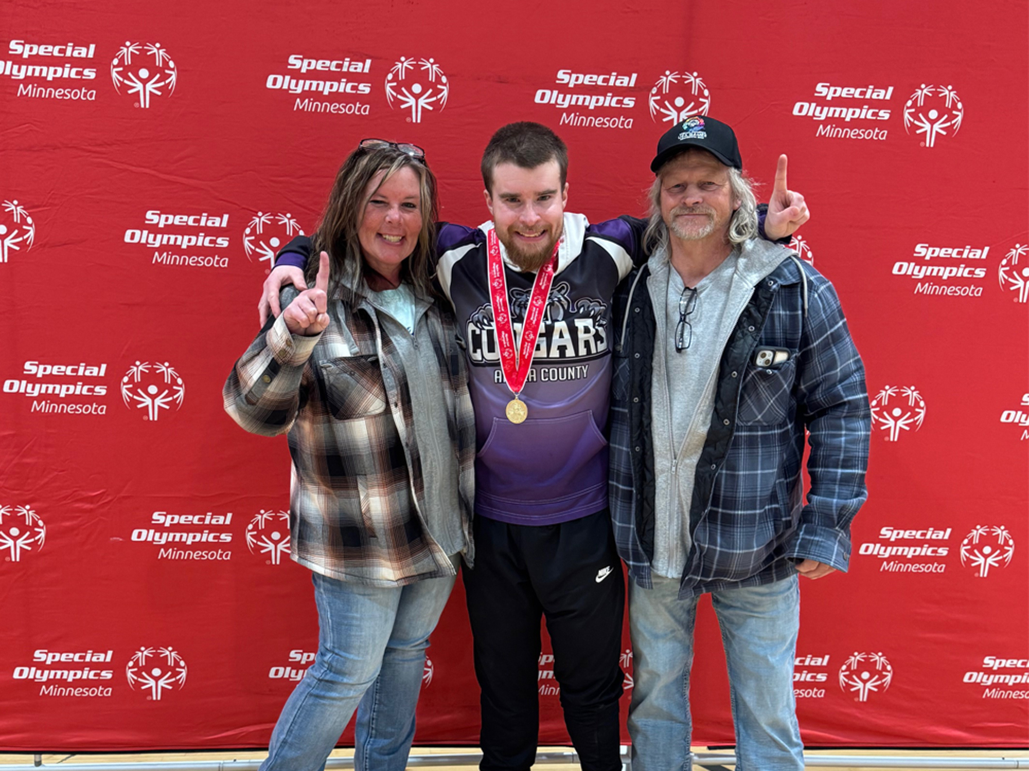 Three people standing in front of a Special Olympics background