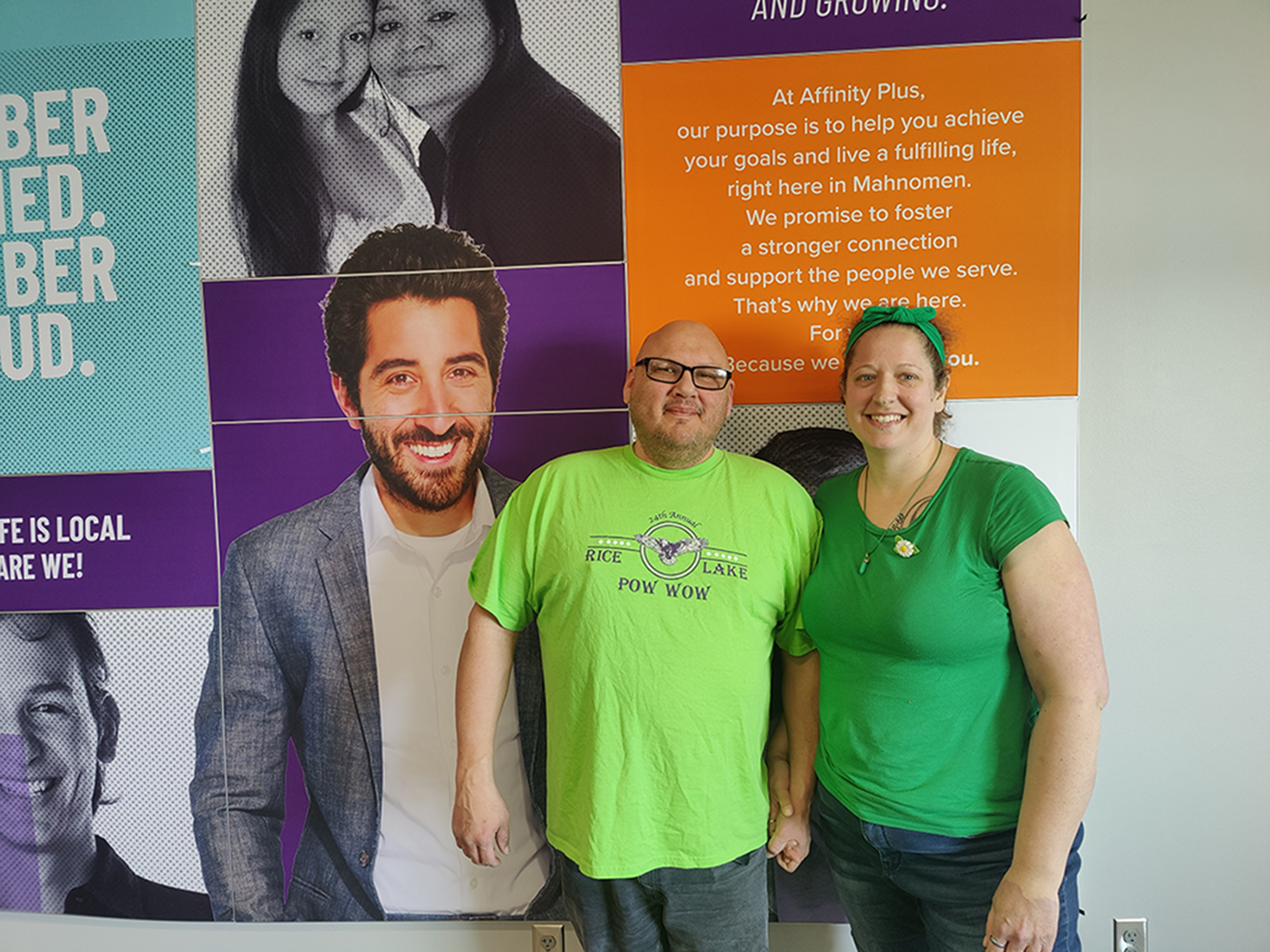 A couple in front of brand wall at the Mahnomen branch