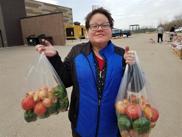A person holding a bag of fresh vegetables in each hand