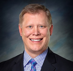 A man against a blue & gray background