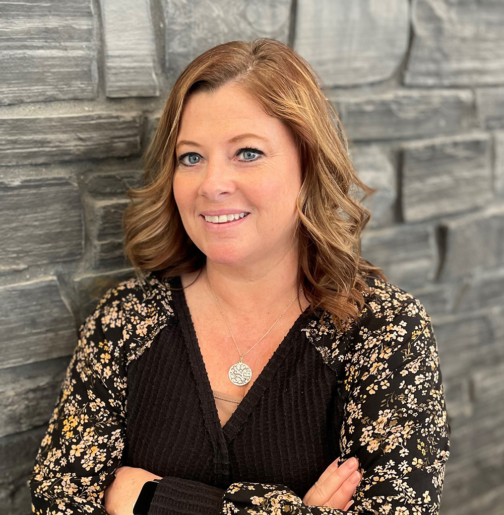 A woman posing with her arms crossed with a brick background