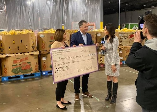 presenting check to a woman with a microphone and camera guy