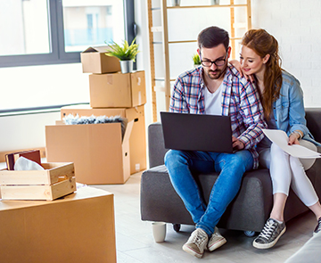 A couple looking at paperwork surrounded by moving boxes