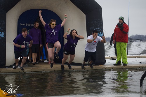 four people jumping in a frozen lake
